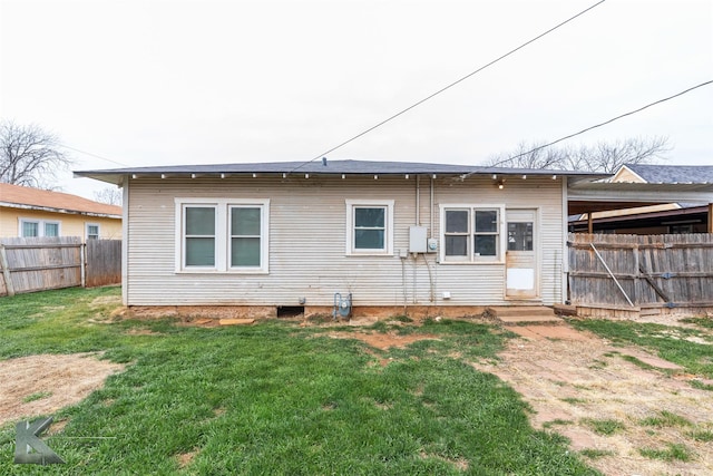 rear view of property featuring entry steps, fence, and a yard