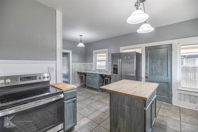 kitchen featuring a kitchen island, wood counters, pendant lighting, and stainless steel appliances