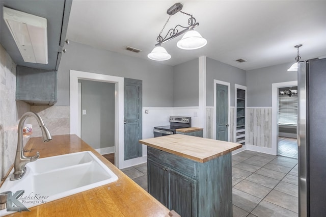 kitchen featuring visible vents, stainless steel appliances, a sink, and pendant lighting