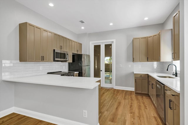 kitchen with stainless steel appliances, a peninsula, a sink, visible vents, and light countertops