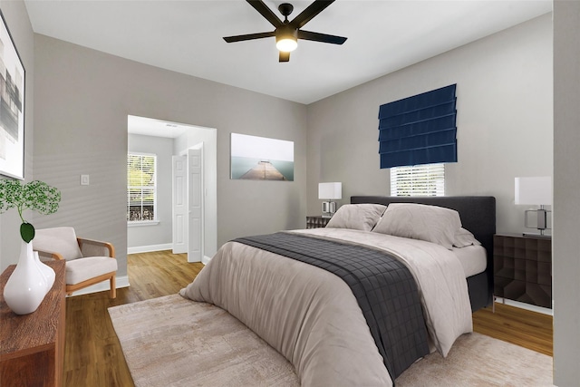 bedroom with a ceiling fan, baseboards, and light wood finished floors