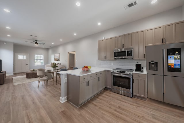 kitchen featuring stainless steel appliances, light countertops, visible vents, open floor plan, and a peninsula