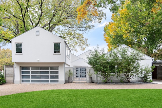 view of front of home featuring decorative driveway, a front yard, and stucco siding