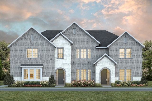 view of front facade with stone siding, a front yard, and brick siding