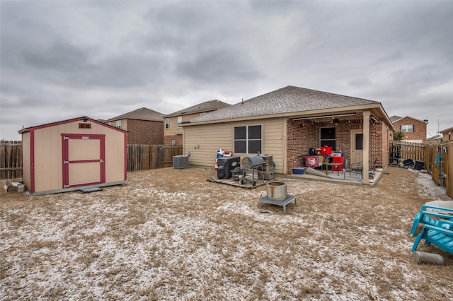 back of property with brick siding, a shed, a fenced backyard, and an outbuilding