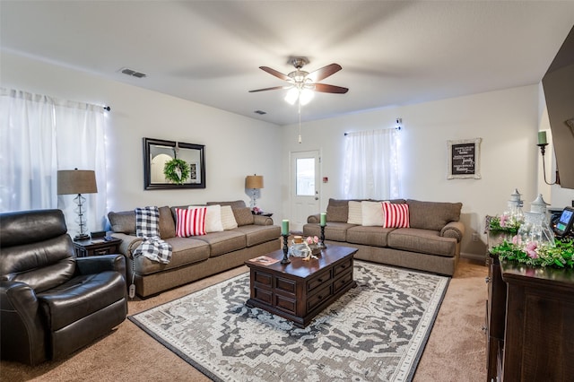 living room with visible vents, a ceiling fan, and light colored carpet