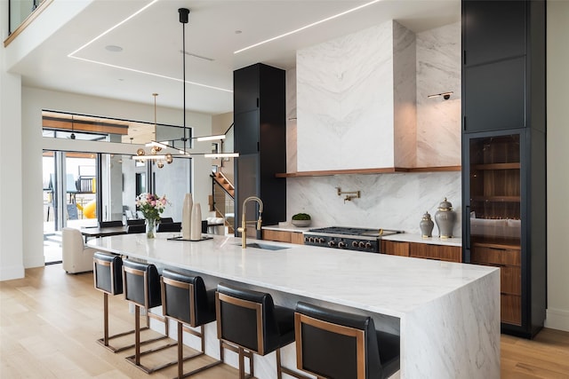 kitchen featuring a kitchen island with sink, a sink, hanging light fixtures, and modern cabinets