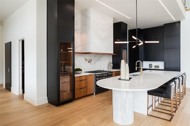 kitchen with an island with sink, modern cabinets, range with two ovens, and a sink