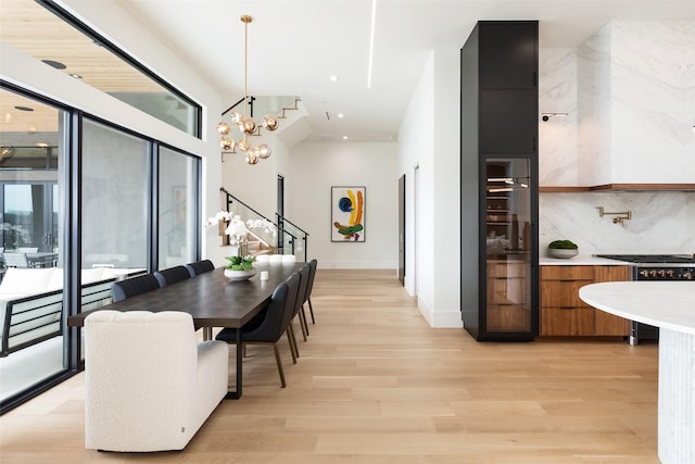 dining room with light wood-type flooring, baseboards, an inviting chandelier, and stairs