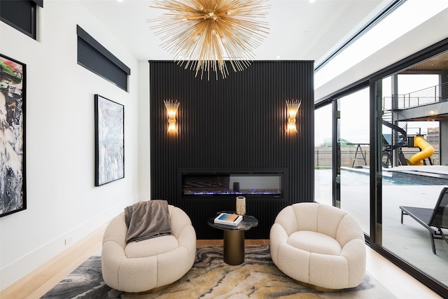 living area featuring a chandelier, light wood-style floors, and baseboards