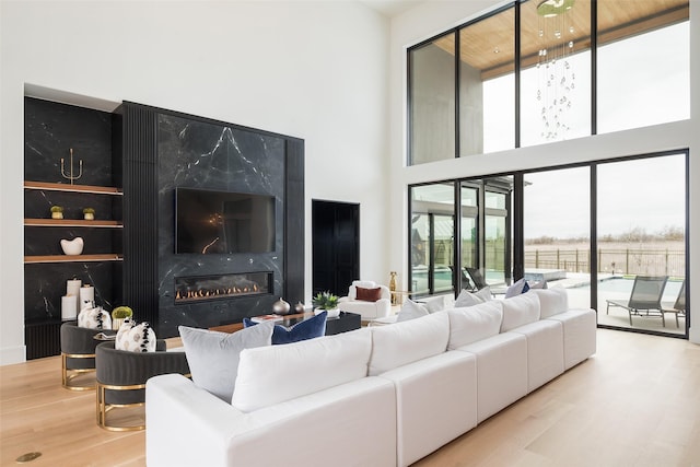 living area featuring a high ceiling, a high end fireplace, and light wood-style floors