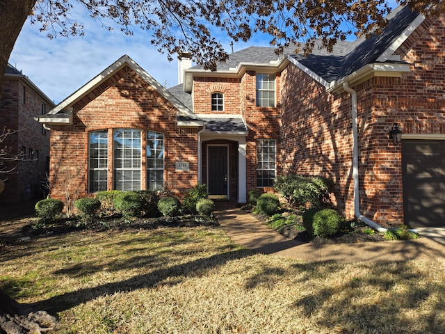 traditional home featuring a garage, brick siding, a chimney, and a front lawn