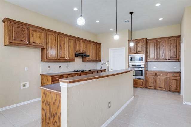 kitchen featuring stainless steel appliances, hanging light fixtures, brown cabinets, and under cabinet range hood