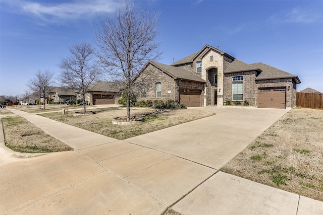 french provincial home with a garage, brick siding, fence, concrete driveway, and roof with shingles