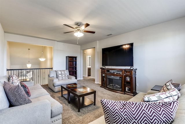 living area with baseboards, visible vents, a glass covered fireplace, ceiling fan, and carpet flooring