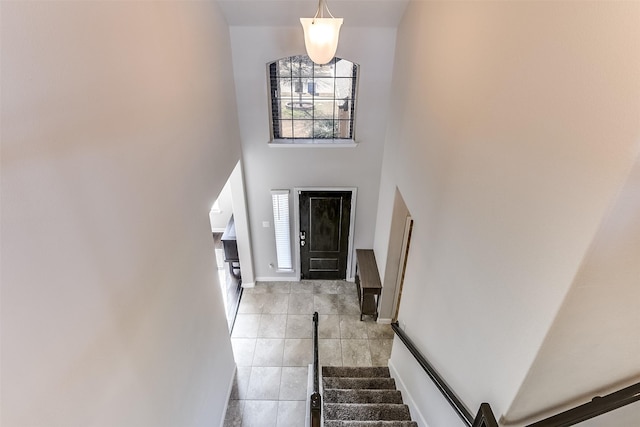 entryway with a towering ceiling, baseboards, stairway, and light tile patterned flooring