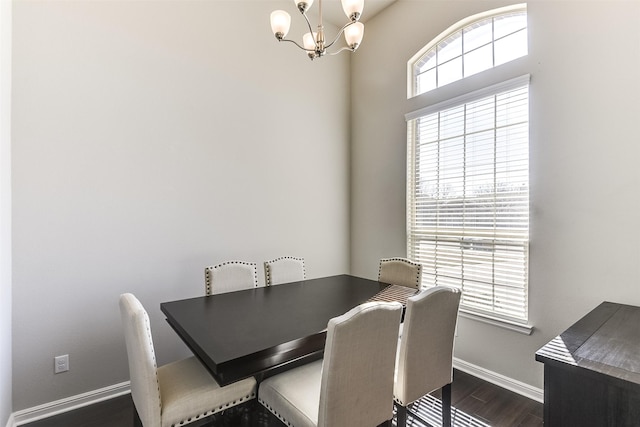 dining room with dark wood-style flooring, a notable chandelier, and baseboards