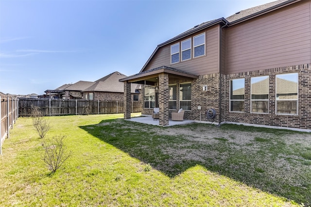 back of property with a patio, a yard, a fenced backyard, and brick siding