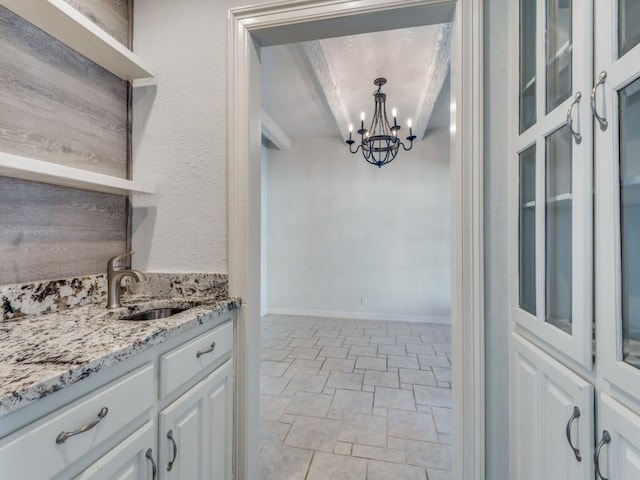 kitchen with light stone counters, a sink, white cabinets, open shelves, and glass insert cabinets