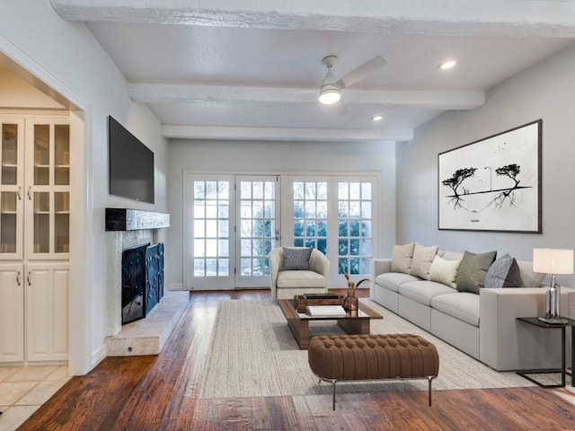 living area with ceiling fan, recessed lighting, a premium fireplace, light wood-type flooring, and beam ceiling