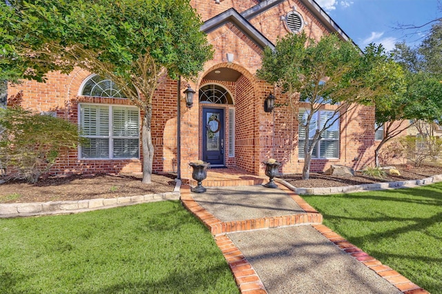 entrance to property with brick siding and a lawn