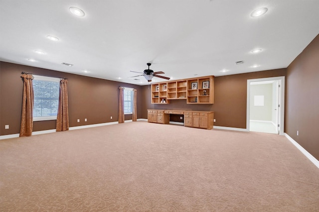 unfurnished living room featuring built in desk, recessed lighting, light colored carpet, ceiling fan, and baseboards