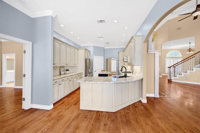 kitchen with light stone countertops, arched walkways, a sink, and freestanding refrigerator