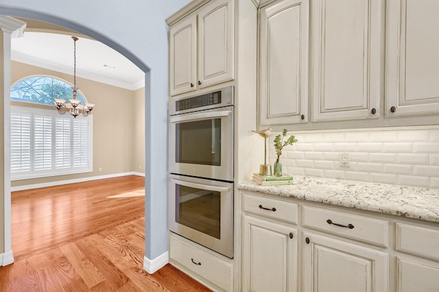 kitchen featuring light wood-style floors, double oven, decorative backsplash, and crown molding