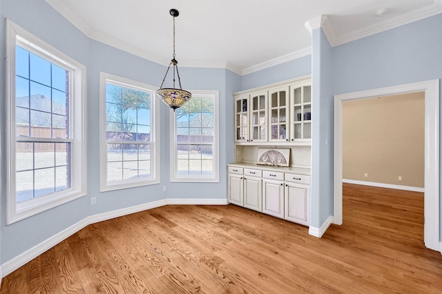 unfurnished dining area with light wood finished floors, baseboards, and ornamental molding