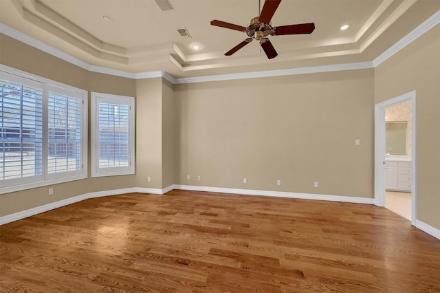 unfurnished room featuring a tray ceiling, crown molding, visible vents, wood finished floors, and baseboards