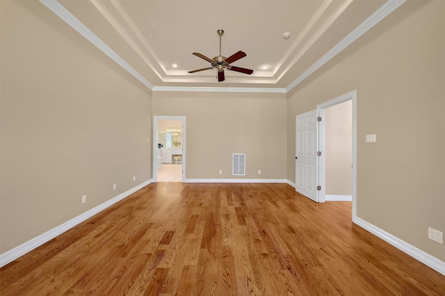 interior space with a tray ceiling, crown molding, visible vents, light wood-style floors, and baseboards