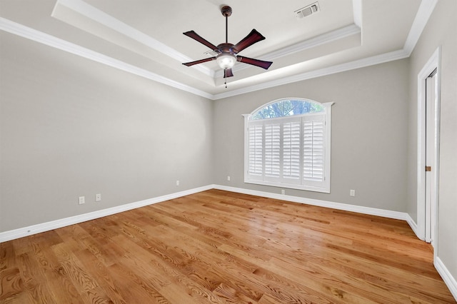 unfurnished bedroom featuring light wood finished floors, a tray ceiling, visible vents, and baseboards