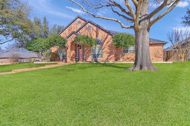 view of front of home with a front yard, brick siding, and fence