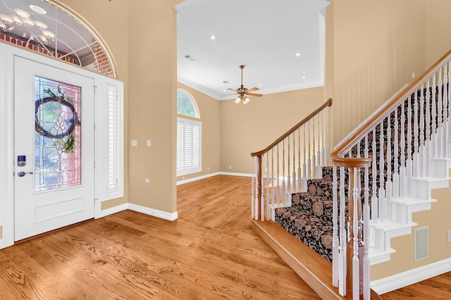 foyer entrance featuring stairs, crown molding, baseboards, and wood finished floors