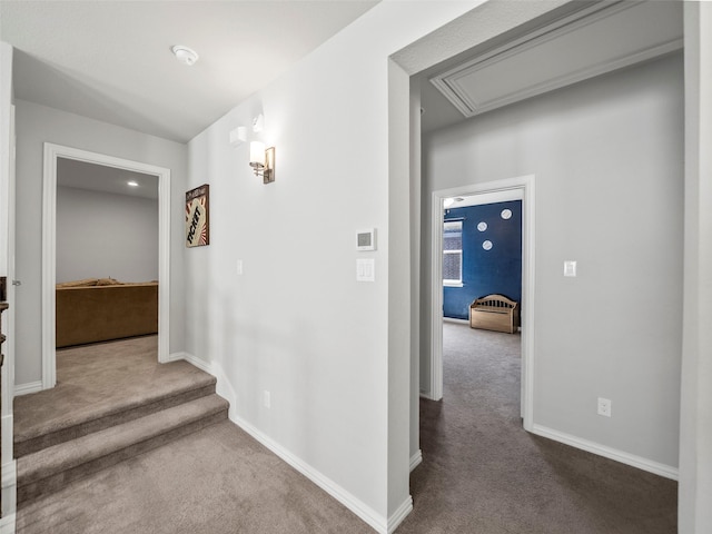 hall featuring carpet, attic access, and baseboards