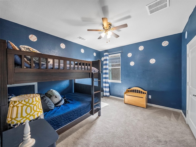 carpeted bedroom with a ceiling fan, visible vents, a textured wall, and baseboards