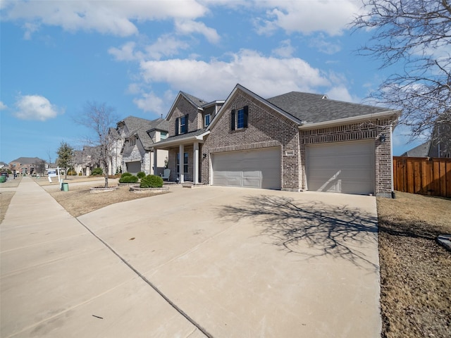 view of front of home with brick siding, fence, a garage, a residential view, and driveway