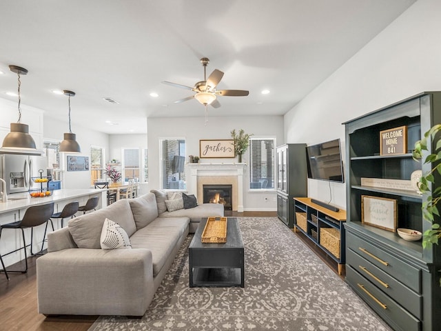 living area with dark wood finished floors, recessed lighting, visible vents, a glass covered fireplace, and ceiling fan