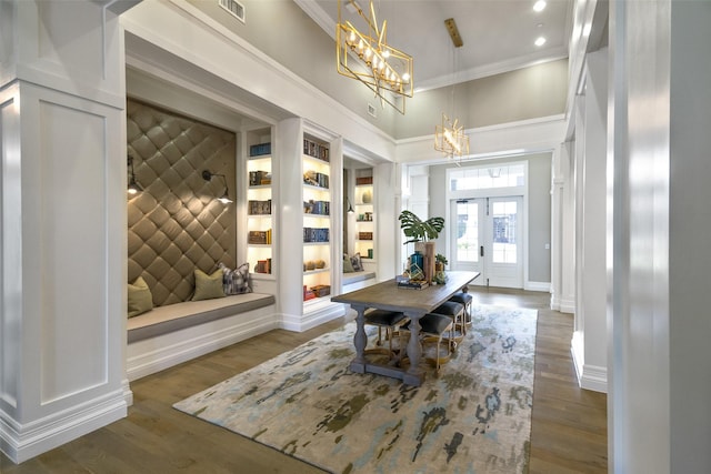 dining room with dark wood-style flooring, visible vents, baseboards, built in features, and ornamental molding