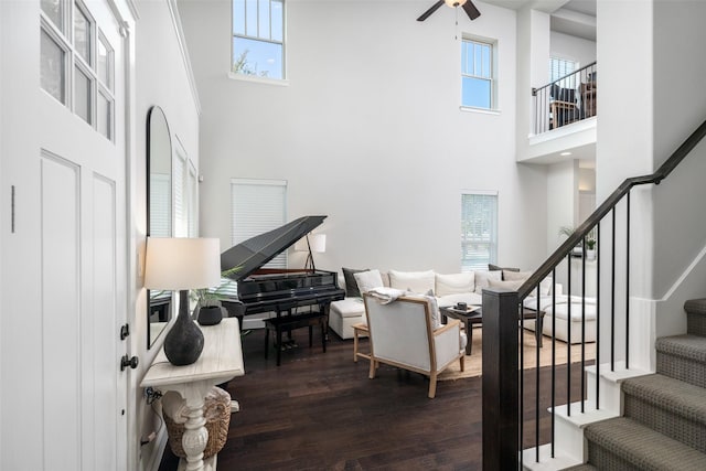 interior space featuring ceiling fan, stairway, dark wood finished floors, and a towering ceiling