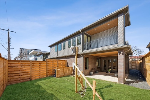 rear view of property featuring a patio area, a fenced backyard, a lawn, and brick siding