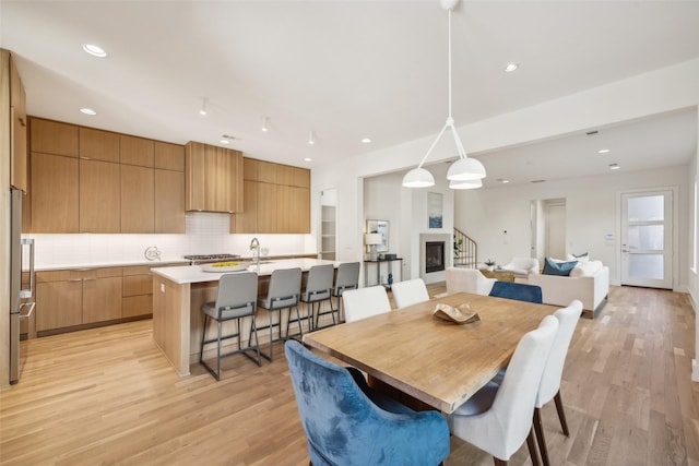 dining room featuring recessed lighting, a glass covered fireplace, and light wood finished floors