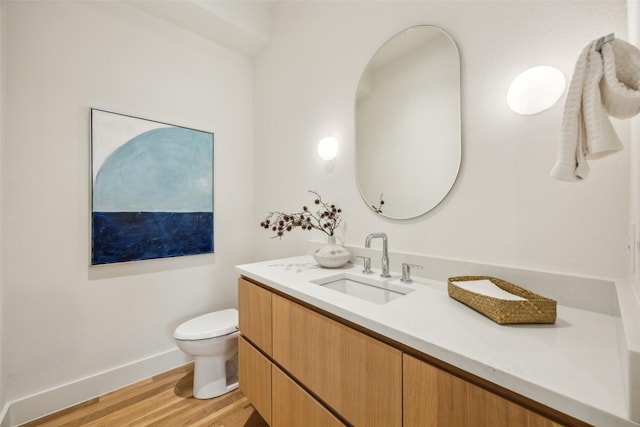 bathroom with baseboards, vanity, toilet, and wood finished floors