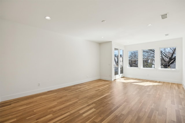 empty room featuring light wood finished floors, recessed lighting, visible vents, and baseboards