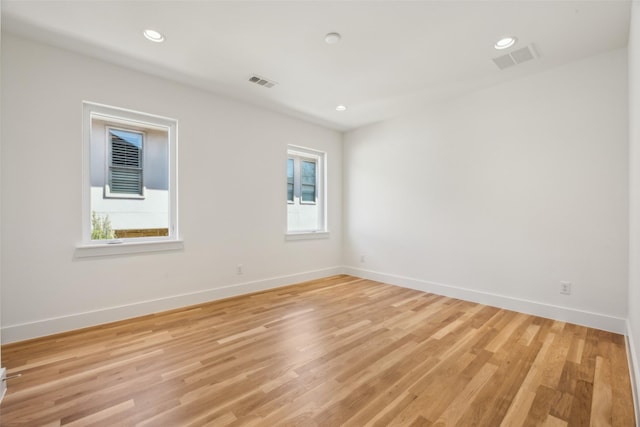 spare room featuring light wood-type flooring, visible vents, and baseboards