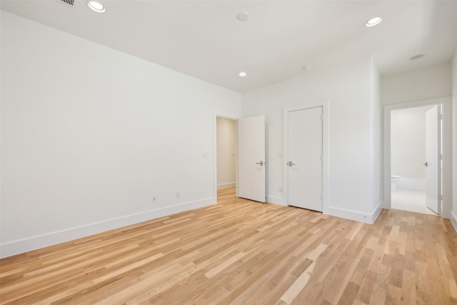 unfurnished bedroom with baseboards, light wood-type flooring, ensuite bath, and recessed lighting