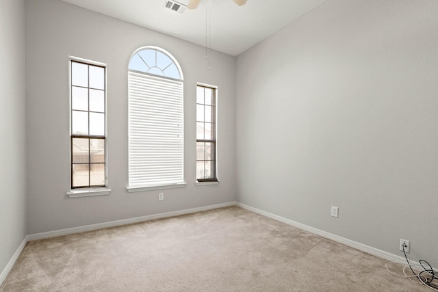 empty room featuring baseboards, visible vents, a ceiling fan, and light colored carpet