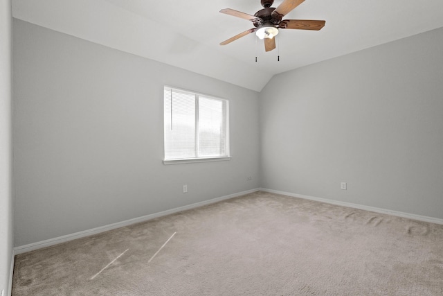 empty room with ceiling fan, baseboards, vaulted ceiling, and light colored carpet