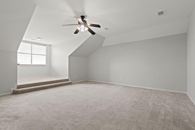 additional living space with baseboards, visible vents, and light colored carpet