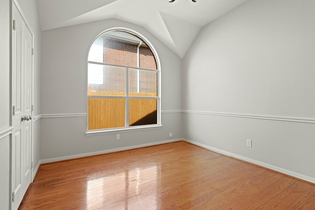 unfurnished room featuring lofted ceiling, light wood-type flooring, and baseboards